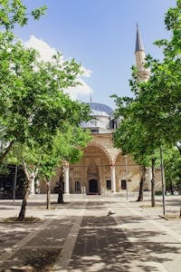 A tranquil mosque surrounded by lush green trees on a clear sunny day.